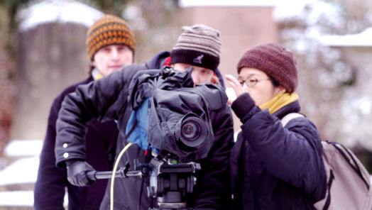 Three apprentices on location behind a camera