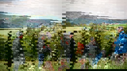 A film crew shoot a scene in a grassy hill landscape