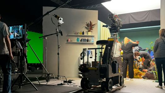 An indoor film set with a dolly in the centre and a team dressing the set
