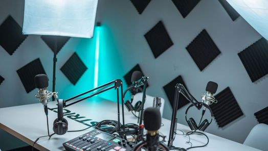 A studio space set up with microphones and headphones around a table with a sound mixer in the centre.