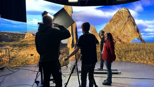 Four people working on a virtual production set with lighting