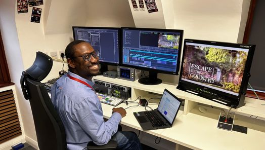 Online editor Jay Francis sits at his workstation in front of computer screens