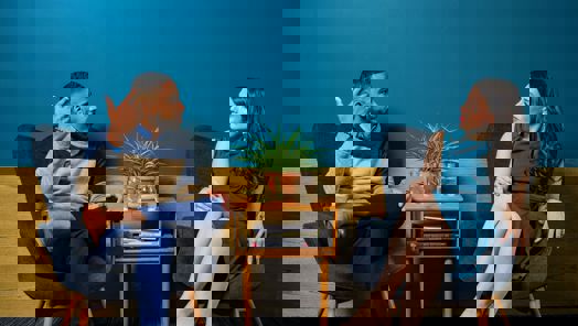 A young man and a young woman sat at a coffee table in conversation