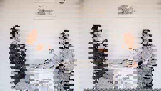 Two women sat at a table drinking coffee and chatting