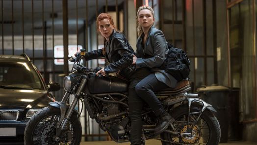 Scarlett Johansson and Florence Pugh on the back of a motorcycle dressed in black leather clothing