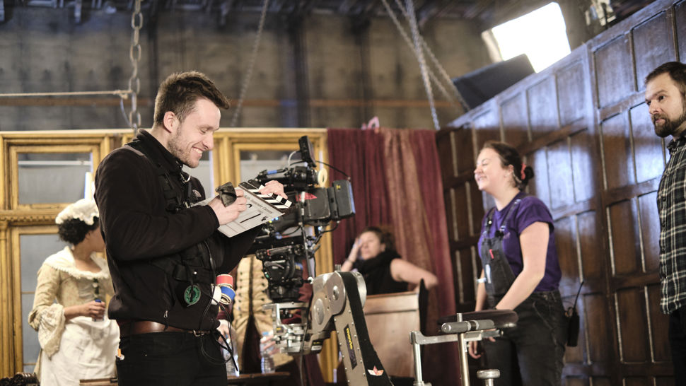 Behind the scenes image of cameraman and other crew on set of a period drama