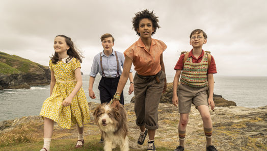 Still of young cast of The Famous Five walking toward the camera away from a cliff edge